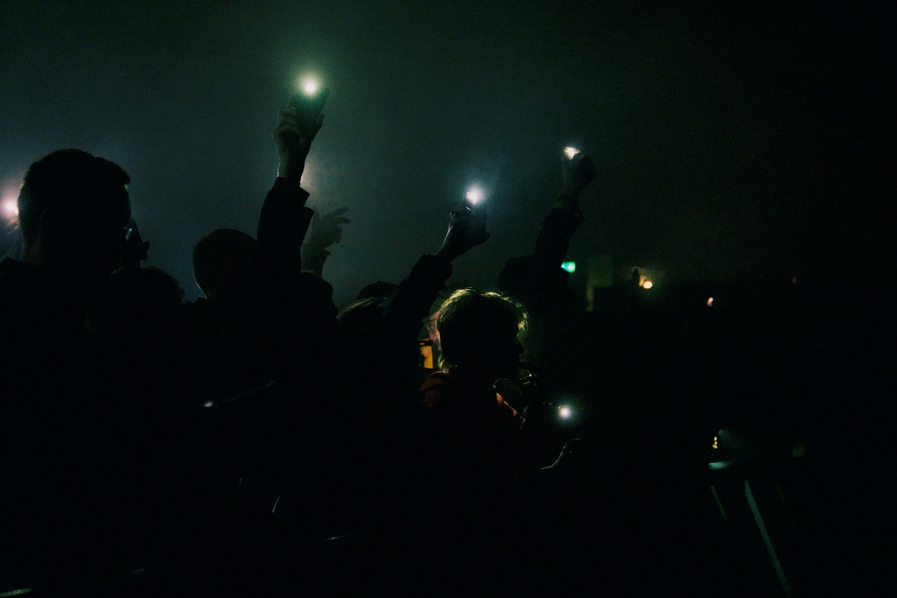 People hold up their mobile phones with the torches on during a performance at Roskilde festival