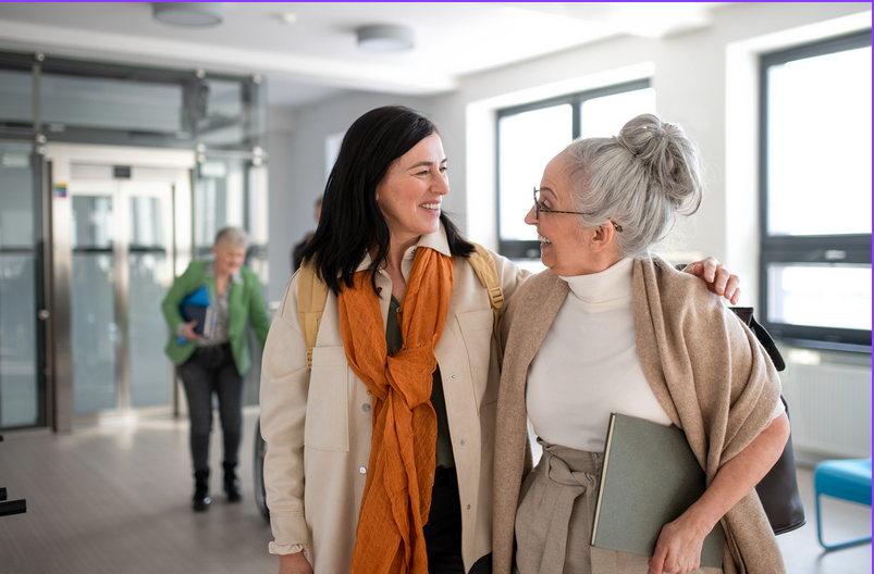 Image of two women smiling, one is older than the other. They are in a univeristy building. 